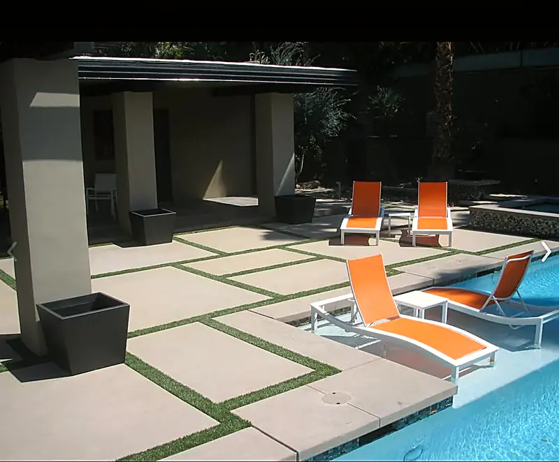 Modern pool deck with geometric concrete pads and turf strips